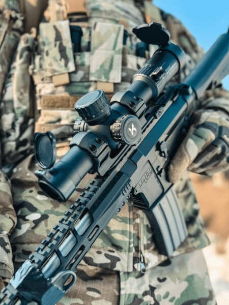 Celownik Vortex Optics szczegółowo na nowoczesnym karabinie szturmowym z montażem na szynie Picatinny, strzelec w kamuflażu. Foto: Rigad