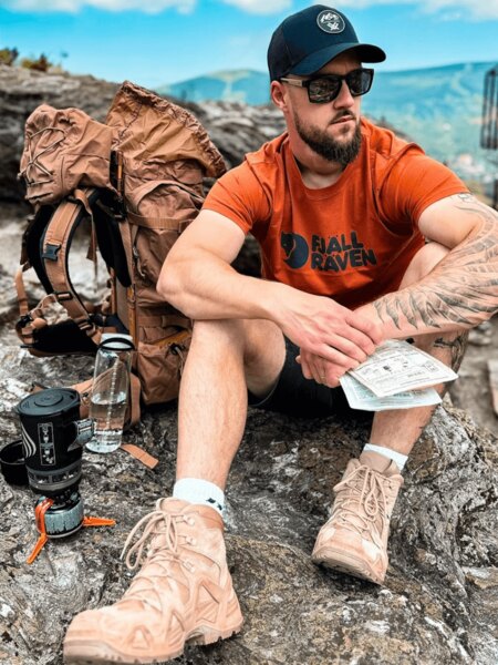 Turysta outdoorowy z plecakiem, czapką z daszkiem i wodą jako ochrona przed udarem słonecznym. Foto: Rigad
