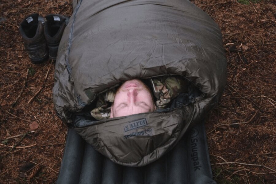 Mężczyzna w maskowaniu leży na dmuchanej karimacie w śpiworze Softie<sup>&reg;</sup> Elite 5 Snugpak<sup>&reg;</sup>. Źródło: Rigad, Snugpak