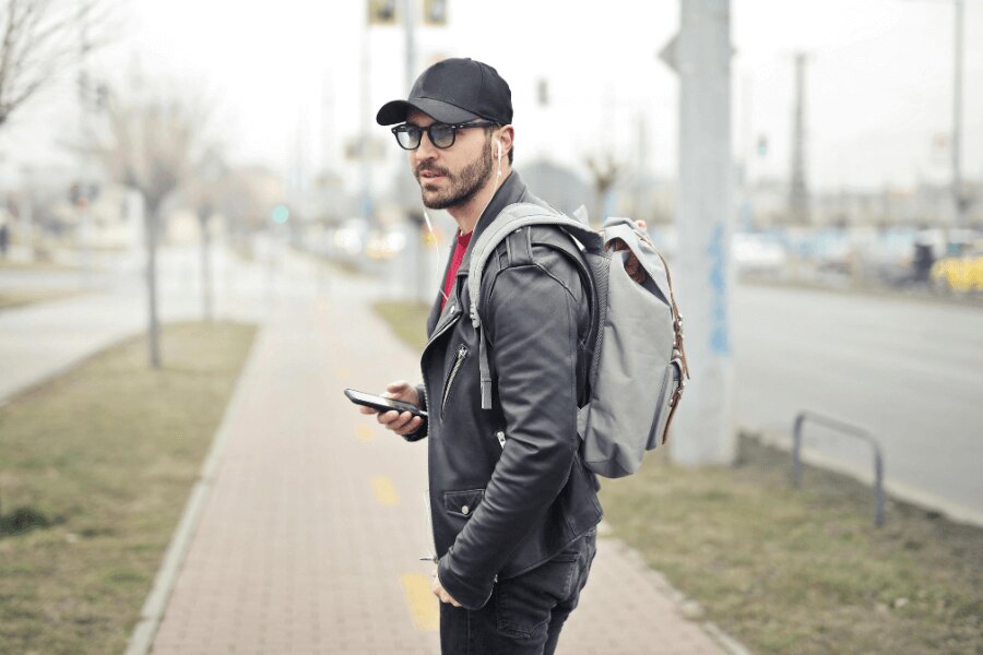 Mężczyzna na ulicy z plecakiem i telefonem komórkowym. Źródło: https://www.pexels.com/cs-cz/foto/845457/
