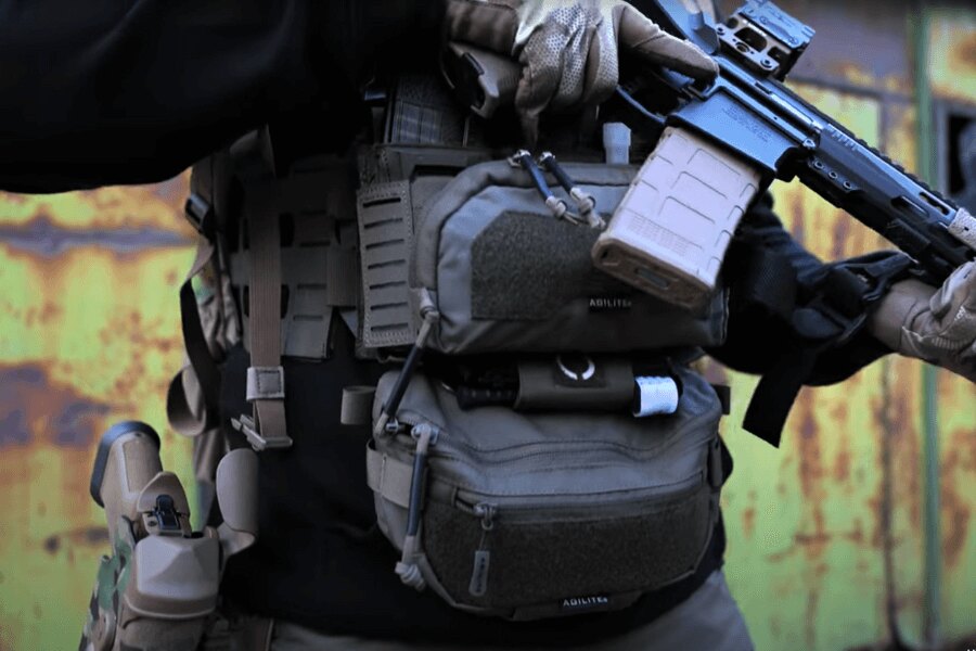 Mężczyzna z Chest Rig Reaper™ Agilite Gear<sup>&reg;</sup> wyposażonym w ładownice i z długą bronią. Źródło: Rigad - video