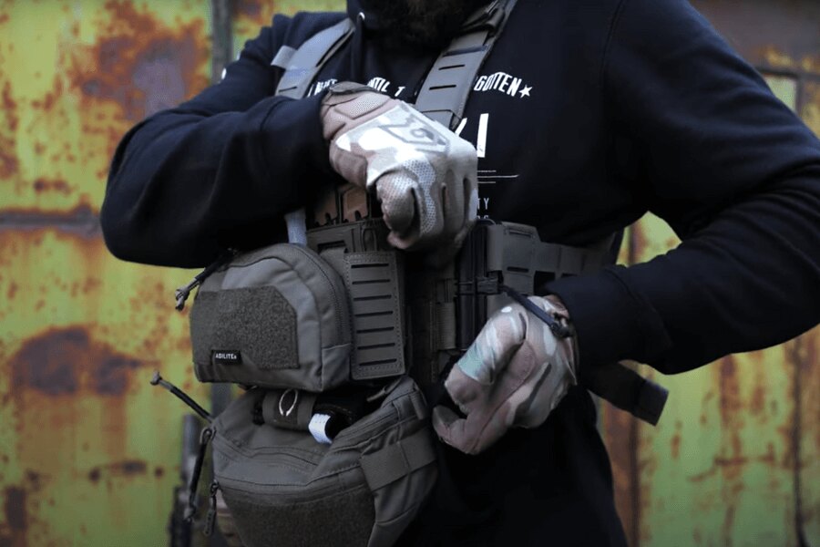 Mężczyzna z Chest Rig Reaper™ Agilite Gear<sup>&reg;</sup> z zamontowanymi ładownicami dostosowuje ustawienia. Źródło: Rigad - wideo