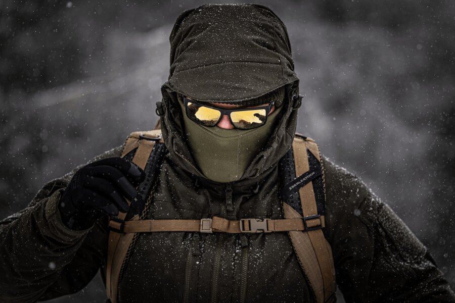Turysta podczas zimowej zamieci w wytrzymałej izolowanej kurtce Helikon-Tex Yukon z balaklawą i goglami przy wymagającej zimowej wspinaczce. Foto: Rigad