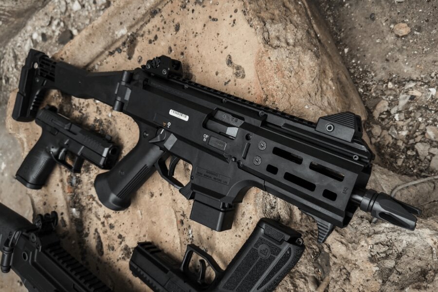 Nowoczesny pistolet maszynowy CZ Scorpion EVO 3 z kolimatorem i teleskopową kolbą leżący na ziemi obok pistoletów i magazynków. Foto: Rigad