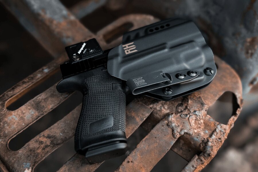 Pistolet z kolimatorem schowany w czarnym kaburze IWB RH Holsters.