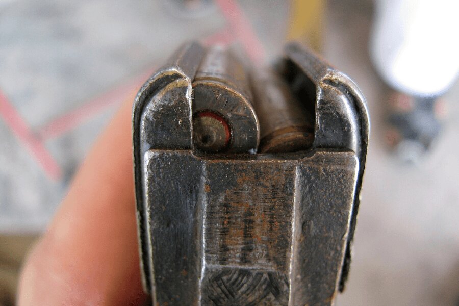 Szczegóły górnej części zużytego stalowego magazynka AK-47 z nabojami kalibru 7,62 × 39 mm.