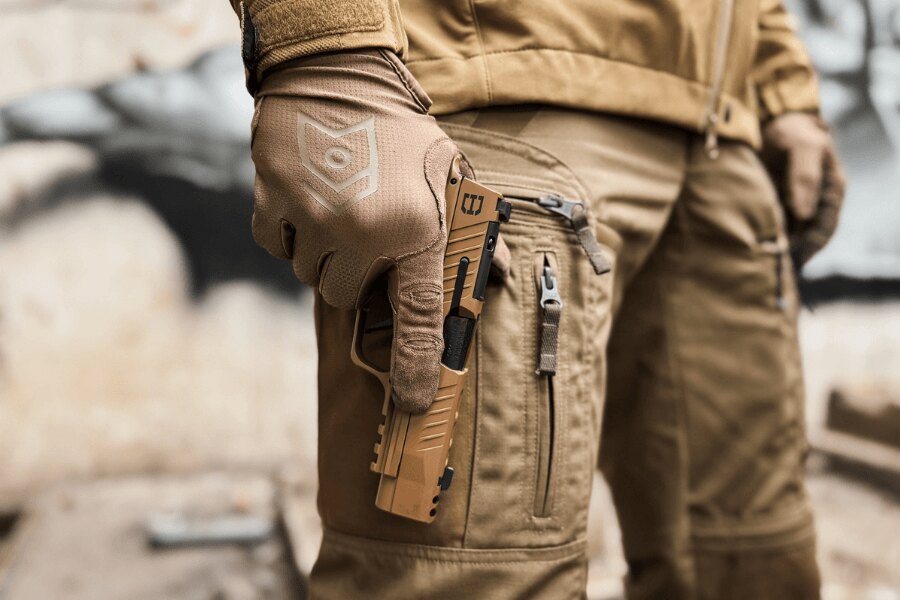 Strzelec w rękawiczkach wyjmuje piaskową pistolet z kabury.